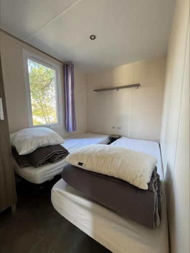 two beds in a small room with a window at Au coeur de la pinède in Camiers