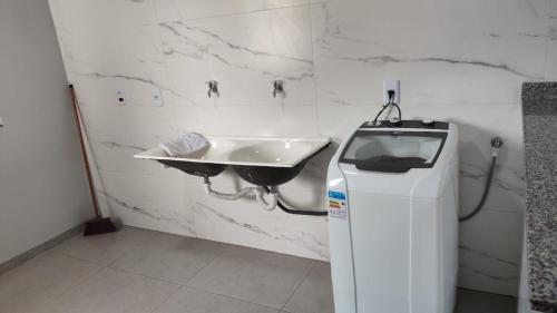 a bathroom with a sink and a water heater at Apartamento 4 completo centro in Sorriso
