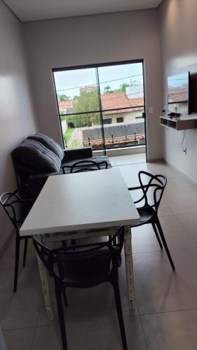 a table and chairs in a living room with a window at Apartamento 4 completo centro in Sorriso