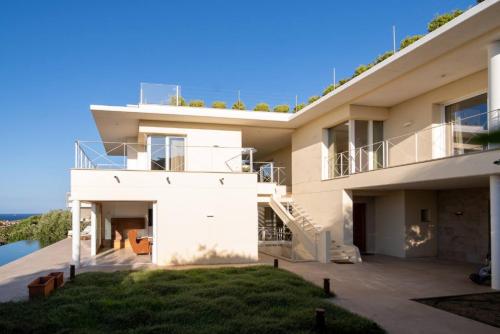 a large white house with a balcony and a yard at Villa Dea overlooking the harbor of Porto Cervo in Porto Cervo