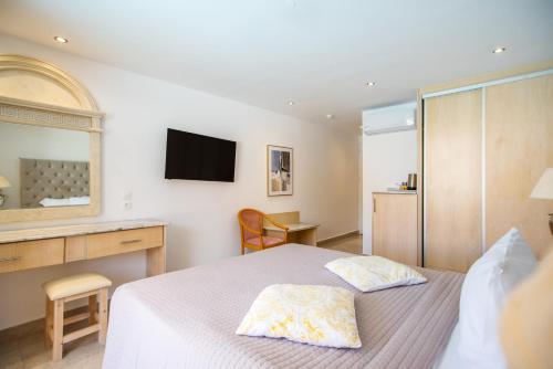 a bedroom with a bed and a television on the wall at Cavomarina Beach- Adults Only in Kavos