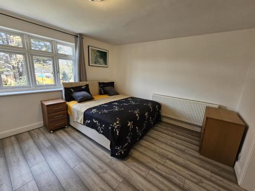a bedroom with a bed and a dresser and two windows at Fantastic 4 Apartments in Dagenham Dock