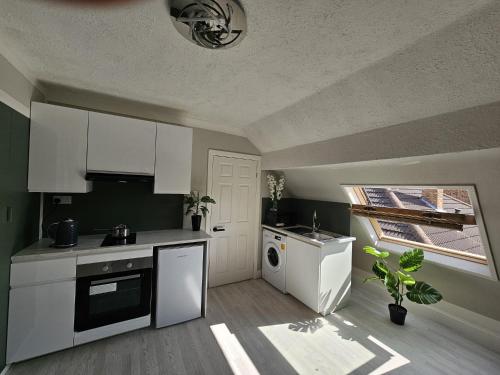 a kitchen with white cabinets and a dishwasher at Fantastic 4 Apartments in Dagenham Dock