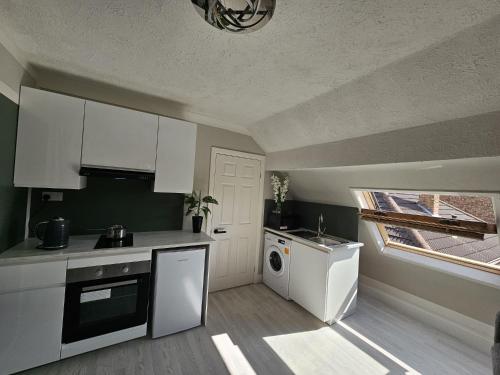 a kitchen with white cabinets and a washing machine at Fantastic 4 Apartments in Dagenham Dock