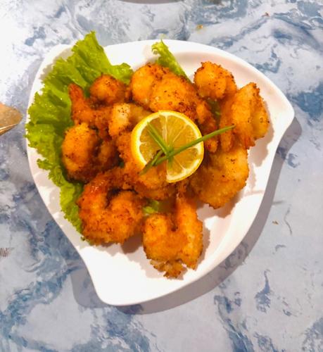 a plate of shrimp with lettuce and a lemon at Dosplaya Ecocamp in El Nido