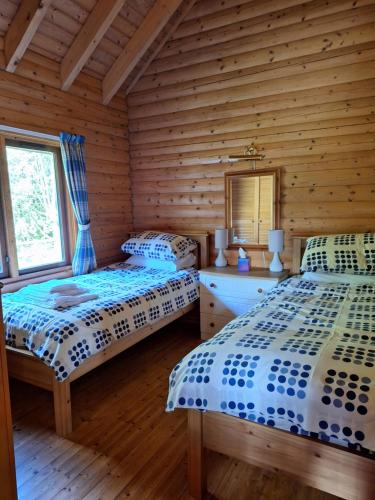 two beds in a room with wooden walls at Springburncabins in Elgin