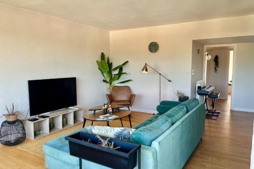 un salon avec un canapé bleu et une télévision à écran plat dans l'établissement Evasion surf & sunset - Parking Gratuit, à Les Sables-dʼOlonne