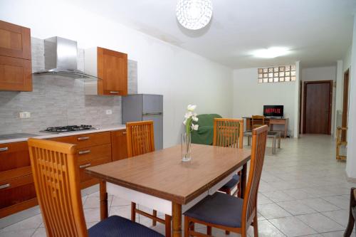 a kitchen and dining room with a wooden table and chairs at Elegante per 6 a due passi dalla spiaggia in Nettuno