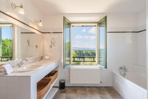 La salle de bains est pourvue de 2 lavabos et d'une grande fenêtre. dans l'établissement Le Mas Elaïa, votre havre familial avec piscine privée, à Eyragues