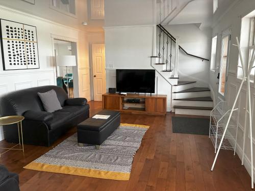 a living room with a black couch and a television at Au Sommet du Lac Magog in Magog-Orford
