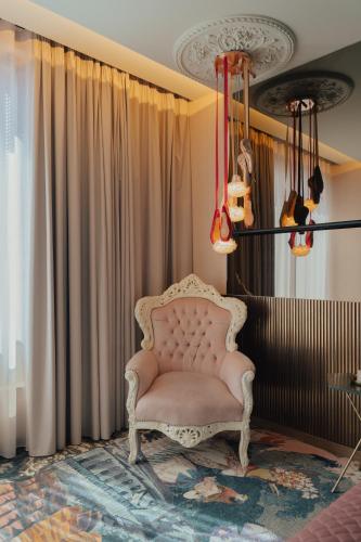 a pink chair sitting in a room with curtains at Hotel Leiriartem by Grupo Quinta dos Lagos in Leiria