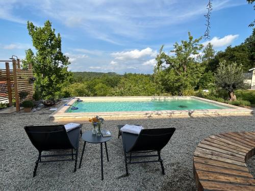 a swimming pool with two chairs and a table in front at Der Hof am Wald in Weichselbaum