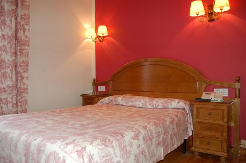 a bedroom with a bed and a red wall at Puente Romano in Cangas de Onís