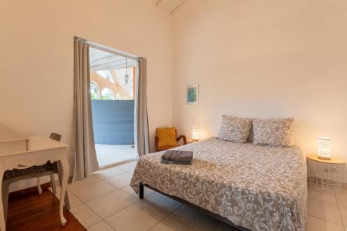 a bedroom with a bed and a desk and a window at Jolibois Lodge & Spa in Le Gosier