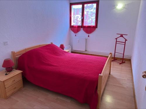 - une chambre avec un grand lit et un couvre-lit rouge dans l'établissement La Muande Appartement famille, à Orcières