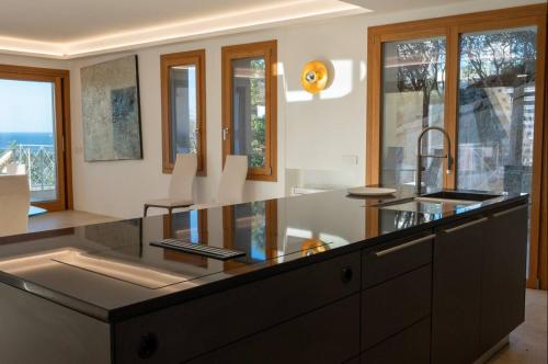 a kitchen with a counter with a sink and windows at Villa Dea overlooking the harbor of Porto Cervo in Porto Cervo