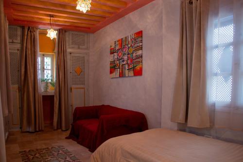 a bedroom with a bed and a chair and a window at Dar Shams Riad Medina de Sousse in Sousse