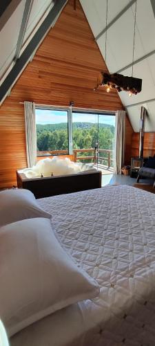 a bedroom with a large bed with a large window at Cabana Santa Cruz 2 in São Francisco de Paula
