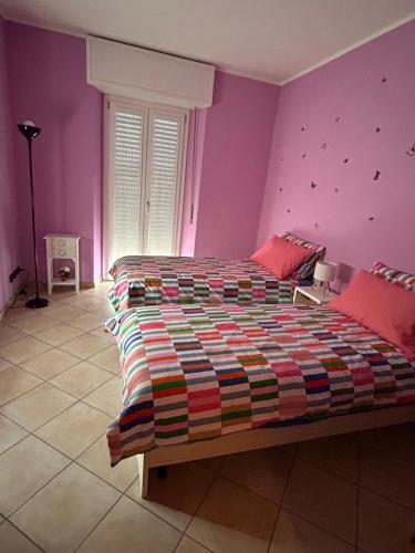 a bedroom with a large bed with purple walls at Casa di Amalia 14 in Biella