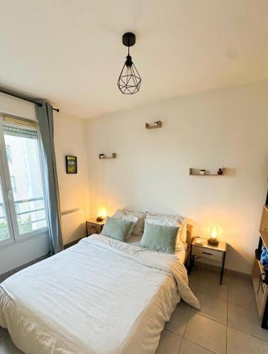 une chambre avec un grand lit blanc avec deux lampes dans l'établissement Appartement 2 pièces, à Saint-Laurent-du-Var