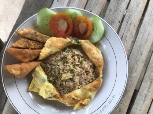 Un plato de comida con carne y verduras en una mesa. en Eger Rise Terrace Bungalow, en Kotaraja