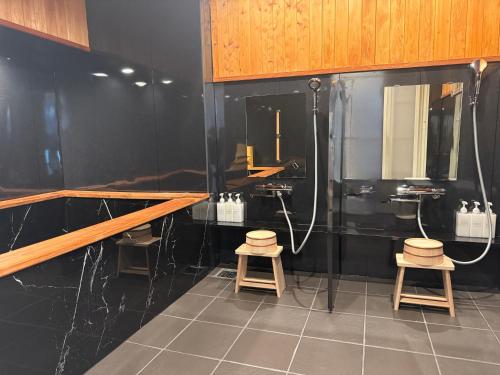 a bathroom with black walls and two stools in it at 琉球の宿 ビーチ至近 伝統とモダンが交差する 恩納村の隠れ家 那覇空港送迎 宿泊者価格レンタカー有 in Ukaji