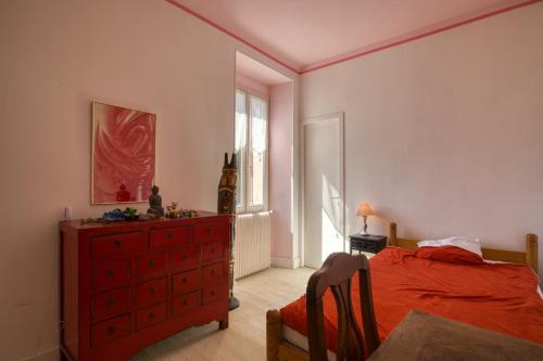 - une chambre avec une commode rouge, un lit et une fenêtre dans l'établissement Maison familiale 4 chambres, à Gujan-Mestras