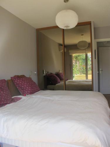 une chambre avec un lit blanc et un grand miroir dans l'établissement ANTIBES, 85 m2, ground floor, large wood terrace, à Antibes