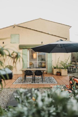 un patio avec une table, des chaises et un parasol dans l'établissement Maison Vintage & Confort - Jardin - 10min mer, à La Seyne-sur-Mer