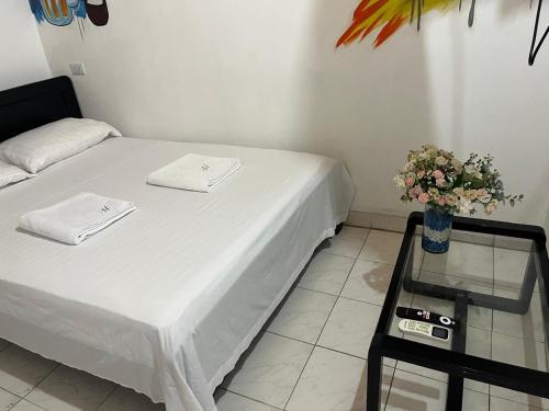 a room with a bed and a table with a vase of flowers at Casa hostal la herradura in San Vicente de Chucurí