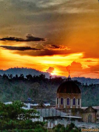 a painting of a building with a sunset in the background at Casa hostal la herradura in San Vicente de Chucurí