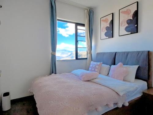 a bedroom with a bed with pillows and a window at 大理顾里海景别墅Dali Guli Sea View Villa Hotel in Dali