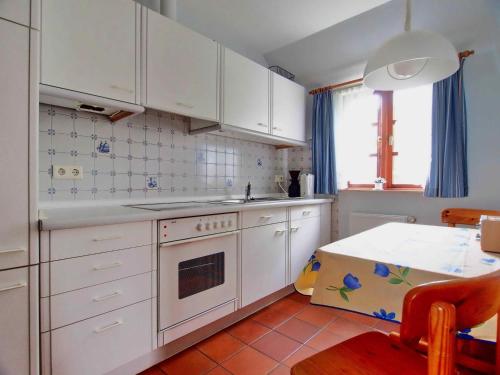 a kitchen with white cabinets and a table in it at Gaestehaus-Bruhn-6 in Alkersum