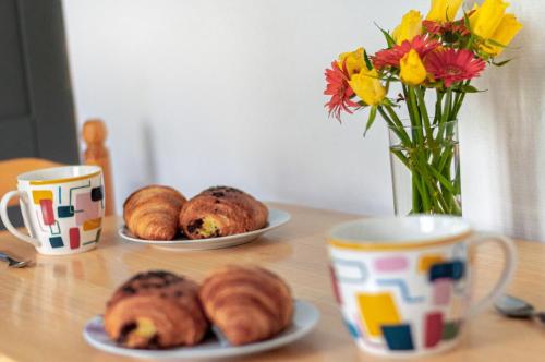 two plates of pastries on a table with cups and flowers at Alexandre et Charline in La Souterraine