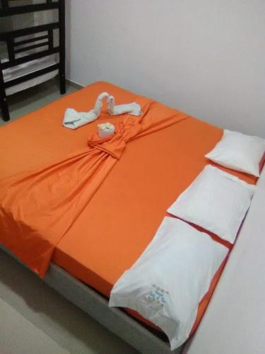 una cama con una manta naranja y sábanas blancas en Hotel vista mar, en Santa Marta
