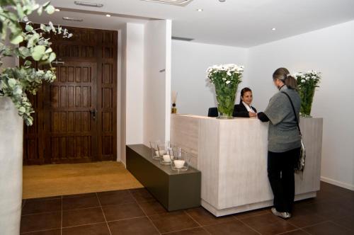a woman standing at a reception desk in a room at Hospedium Hotel Convento de Santa Ana in Atienza