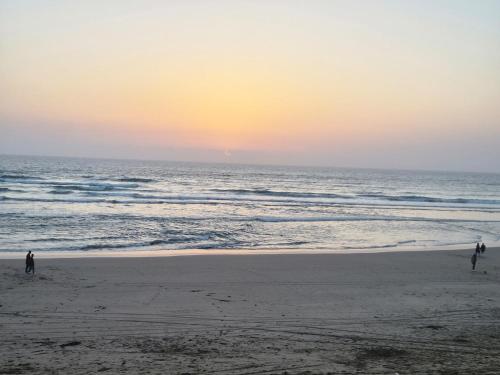 two people walking on the beach at sunset at Seaside Escape - Modern Comfort and Relaxation in Mehdia in Kenitra