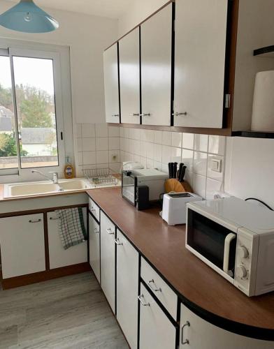 une cuisine avec des placards blancs et un comptoir avec un four micro-ondes dans l'établissement Appartement centre ville Chateau-Renault, à Château-Renault