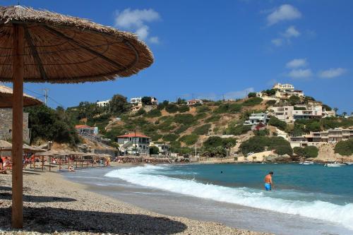 a beach with an umbrella and people in the water at ANATOLI 1 BEACH APARTMET Ligaria in Lygaria