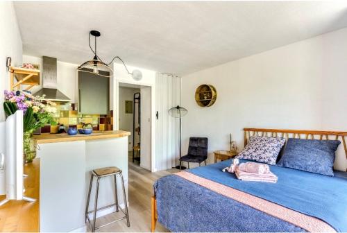 une chambre avec un lit bleu et une cuisine dans l'établissement Studio Les Régates avec loggia et parking gratuit Plage du Grazel Gruissan, à Gruissan