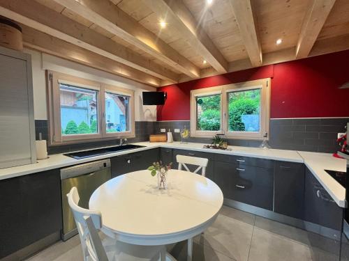 - une cuisine avec une table blanche et des murs rouges dans l'établissement La Maison Magique! Magnifique chalet familial, à Sallanches