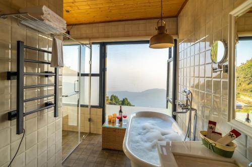 a bathroom with a tub and a large window at The English Country House in Mussoorie