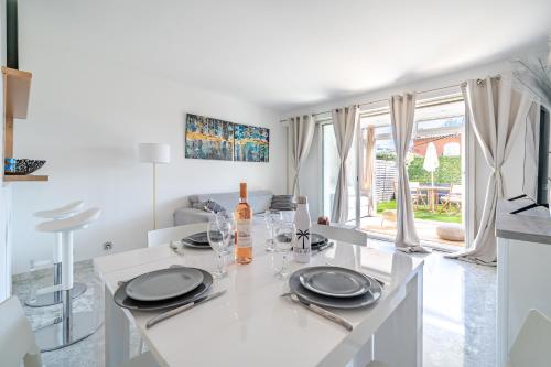 - une cuisine blanche avec une table et des verres à vin dans l'établissement Studio Clim Piscine Nice ouest, à Nice