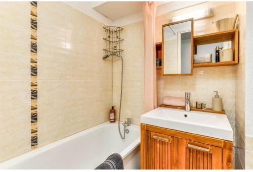 a bathroom with a tub and a sink and a mirror at Studio Les Régates avec loggia et parking gratuit Plage du Grazel Gruissan in Gruissan