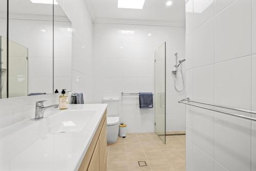 a white bathroom with a sink and a shower at Sunnyside 15B Baldwin St South West Rocks - Full Linen Provided in South West Rocks