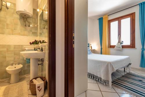 a bathroom with a bed and a sink and a toilet at Sardinia Re - Casa Ginestra in Stintino