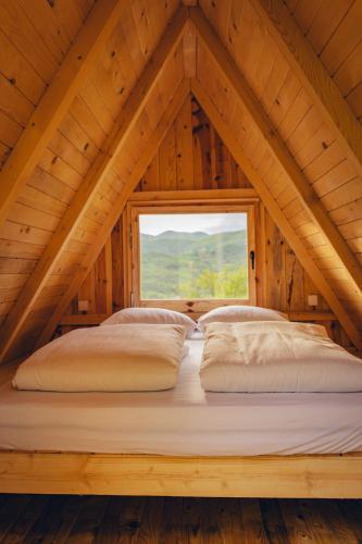 a bed in the attic of a wooden house at Mountain Camp Outdoor Tara in Tjentište