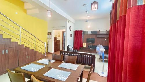 a dining room with a table and red curtains at 4 Bedroom Service Apartment with Kitchen near Velachery - Madipakkam - Pallikaranai in Chennai