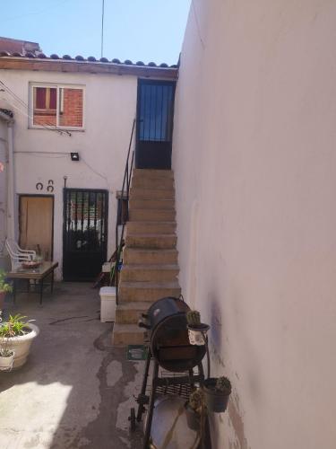 a stairway leading up to a white building with a stair case at Habitación rústica independiente con todas las comodidades, sofacama y ventilador in Tordesillas