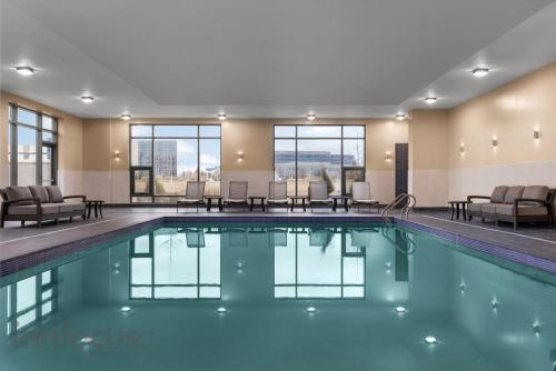 a swimming pool in a hotel with chairs and tables at Hyatt House Mississauga / Airport Corp Center in Mississauga
